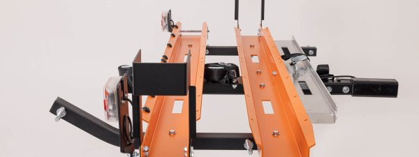End view of Rack N Ride double electric bike hitch carrier rack showing orange wide wheel trays, wheel chocks, black main bar and silver loading ramps